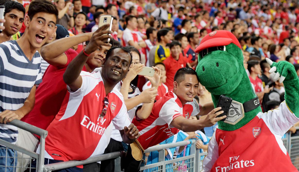 Sosok di balik boneka dinosaurus tersebut adalah pria bernama Jerry Quy. Gunnersaurus telah menjadi maskot klub Arsenal selama 27 tahun. (AP Photo/Joseph Nair)
