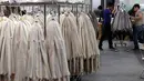 Para pekerja merapikan pakaian yang terbuat dari bulu binatang di Hong Kong International Fur and Fashion Fair di Hong Kong, Sabtu (24/2). (VIVEK PRAKASH/AFP)