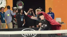 Seorang aktor berpakaian seperti karakter superhero Marvel Thor bermain tenis di Rod Laver Arena saat acara Kids Day menjelang turnamen tenis Australia Terbuka di Melbourne (13/1). (AFP Photo/Paul Crock)