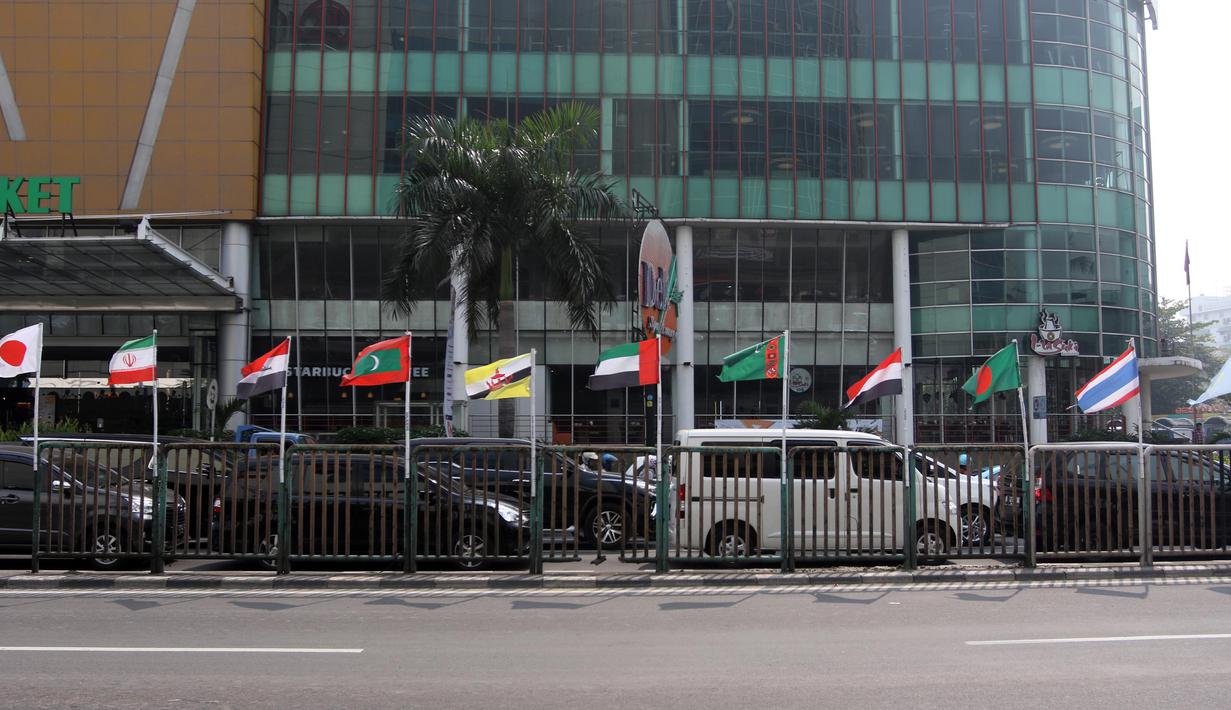 Deretan bendera negara-negara kontestan Asian Games 2018 yang terpasang menggunakan bambu di pagar pembatas Jalan Pluit Selatan Raya, Jakarta, Kamis (19/7). Pemasangan bendera yang diikat di tiang bambu menjadi kontroversi. (Liputan6.com/Arya Manggala)