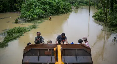 Warga terlihat dievakuasi menggunakan alat berat dari daerah di mana jalan saat ini terendam banjir di Sementeh, dekat Lanchang di negara bagian Pahang Malaysia (6/1/2021). Puluhan orang dievakuasi saat Pahang dilanda gelombang kedua banjir. (AFP/Mohd Rasfan)