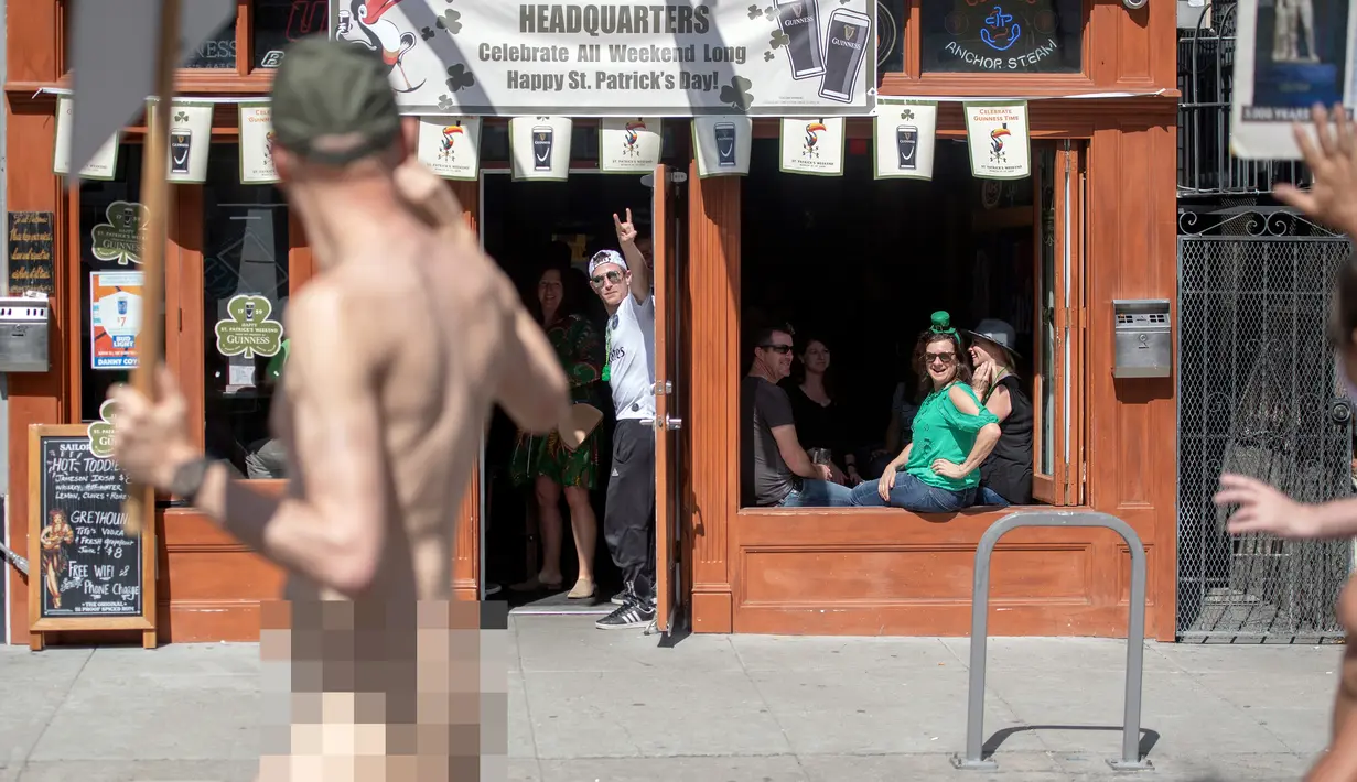 Seorang nudis menyapa warga saat mengikuti acara Nude Love Parade di San Francisco, California, AS, Minggu (17/3). Nudis adalah sebutan bagi mereka yang menjalankan tradisi telanjang. (Josh Edelson/AFP)