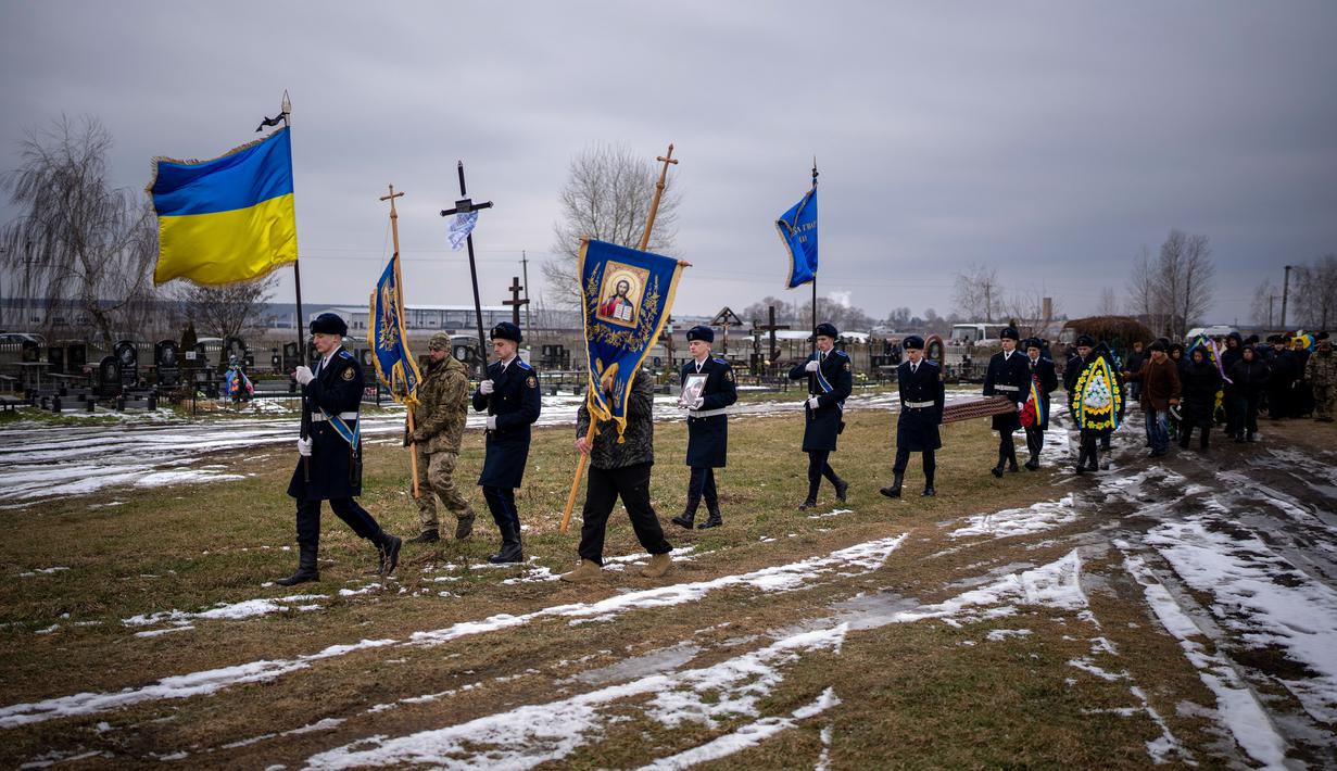 Peti mati Oleksandr Maksymenko (38) dibawa oleh petugas Ukraina selama pemakamannya di kampung halamannya di Kniazhychi, sebelah timur Kyiv, Ukraina, 13 Februari 2023. Oleksandr Maksymenko, seorang warga sipil yang menjadi sukarelawan di angkatan bersenjata Ukraina, tewas dalam pertempuran di daerah Bakhmut. (AP Photo/Emilio Morenatti)