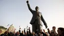 Sejumlah orang bersorak di depan patung Nelson Mandela pada peresmian di kota Ramallah, Palestina, Selasa (26/4). Patung dengan tangan kanan mengepal ke udara itu menjulang dengan ketinggian enam meter dan bobot dua ton. (REUTERS/Mohamad Torokman)