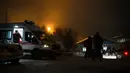 Sebuah ambulans terlihat di wilayah tambang batu bara Listvyazhnaya dengan sekelompok orang berkumpul di dekat sebuah bangunan saat tim penyelamat melakukan operasi pencarian para penambang yang hilang, di wilayah Kemerovo dekat kota Belovo (26/11/2021). (AFP/Alexander Patrin)