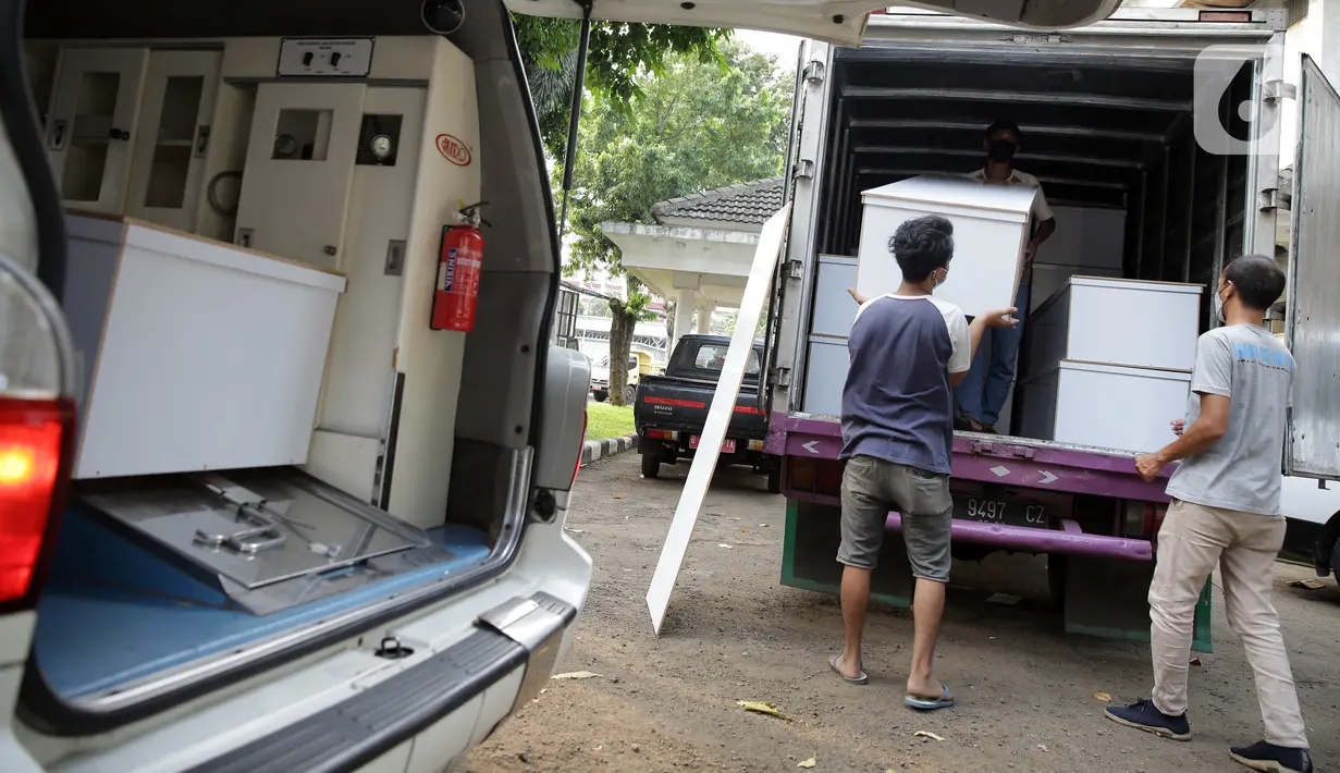 Petugas saat menurunkan peti jenazah COVID-19 untuk didistribusikan ke rumah sakit di TPU Petamburan, Jakarta, Selasa (6/7/2021). Dalam sehari, 100-200 peti jenazah didistribusikan ke sejumlah rumah sakit di DKI Jakarta. (Liputan6.com/Faizal Fanani)