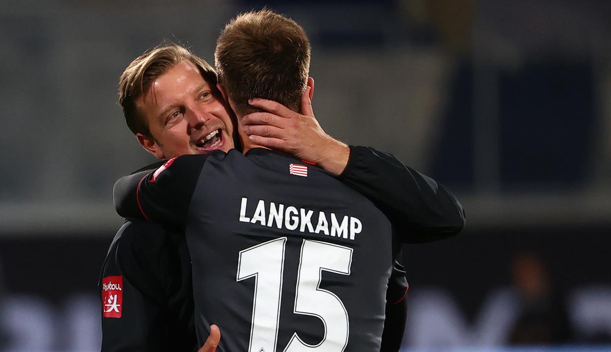 Pelatih Werder Bremen, Florian Kohfeldt, memeluk Sebastian Langkamp setelah timnya berhasil bertahan di kompetisi Bundesliga usai menahan imbang Heidenheim 1846 di laga play-off leg kedua, Selasa (7/7/2020) dini hari WIB. Bremen bermain imbang 2-2 atas Heidenheim. (AFP/Kai Pfaffenbach/pool)