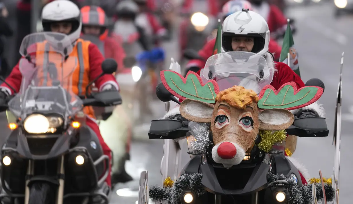 Pengendara sepeda motor yang mengenakan kostum Sinterklas mengendarai motor mereka selama parade Sinterklas di Beograd, Serbia, Minggu (26/12/2021). Mereka melakukan konvoi menuju rumah sakit anak-anak untuk membagikan mainan hadiah Natal kepada pasien di sana. (AP Photo/Darko Vojinovic)