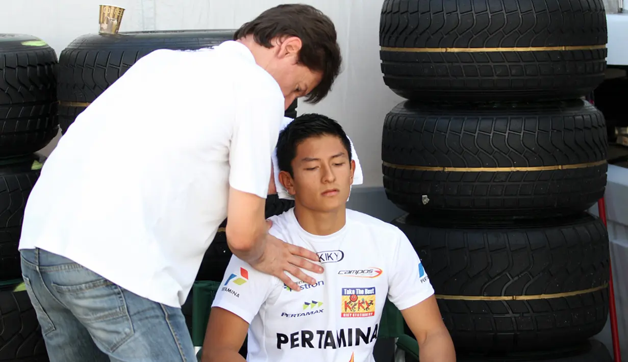 Pelatih fisik Rio Haryanto, Moises Vila Blanch, melakukan terapi pijat leher saat sesi pemanasan jelang Feature Race GP2 Seri Italia di Sirkuit Monza, Italia, Sabtu (5/9/2015) siang waktu setempat. (Bola.com/Reza Khomaini)