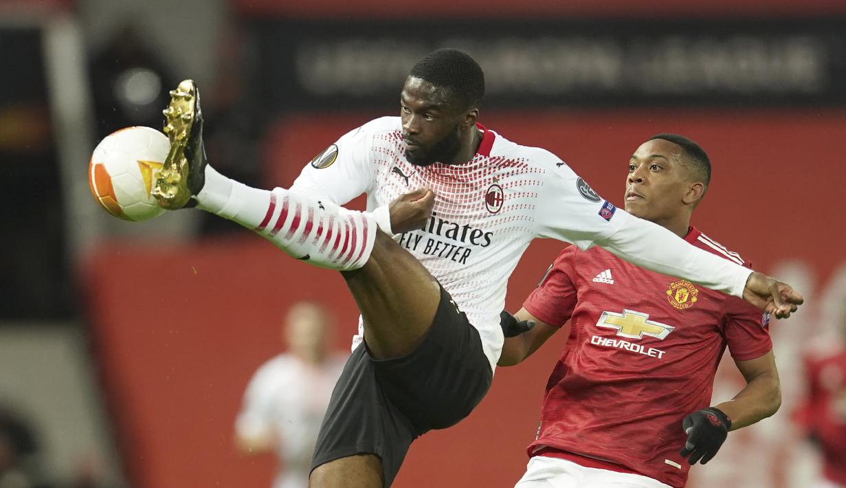 Bek AC Milan, Fikayo Tomori menendang bola dari kawalan striker Manchester United, Anthony Martial pada leg pertama babak 16 besar Liga Europa di Old Trafford, Inggris, Jumat (12/3/2021). Milan berhasil mencuri satu gol tandang yang akan jadi modal berharga untuk leg kedua. (AP Photo/Dave Thompson)