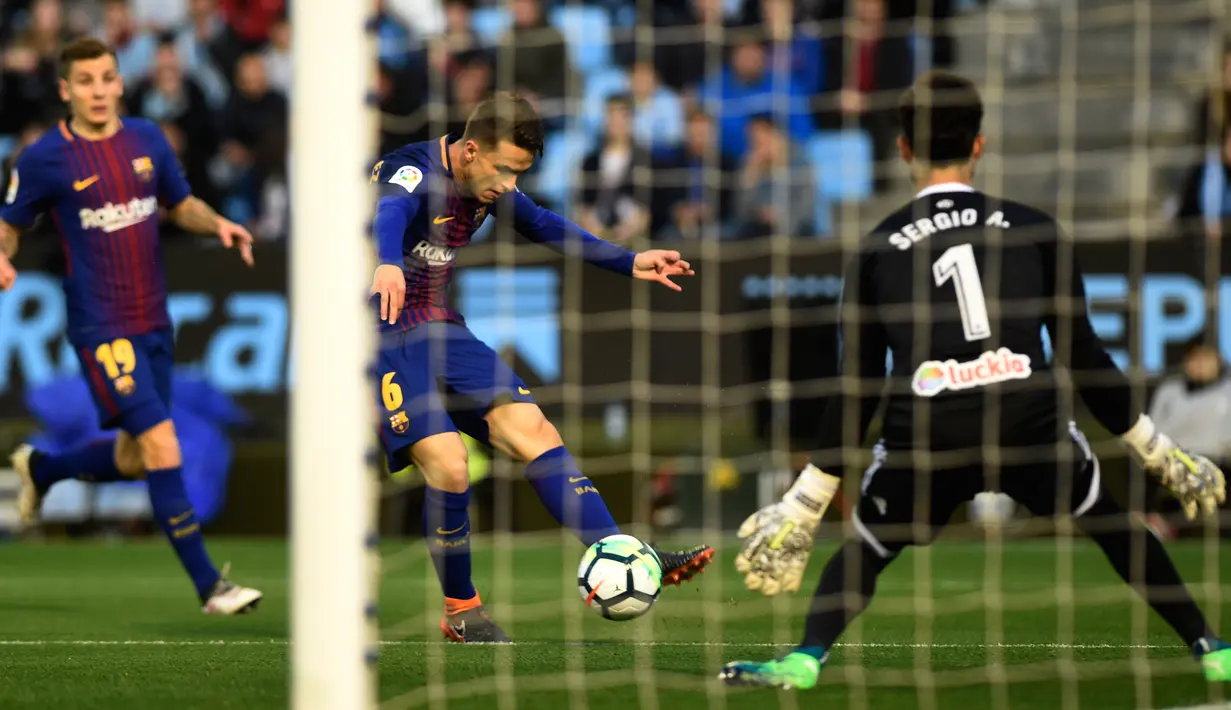 Gelandang Barcelona, Denis Suarez menendang bola di depan kiper Celta Vigo, Sergio Alvarez pada laga pekan ke-33 La Liga di Estadio de Balaidos, Selasa (17/4). Tampil dengan sepuluh pemain, Barcelona harus puas dengan hasil imbang 2-2 (MIGUEL RIOPA / AFP)
