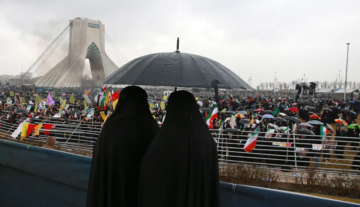 Dua wanita memakai payung saat menghadiri upacara peringatan 40 tahun Revolusi Islam Iran di Menara Kebebasan, Teheran, Senin (11/2). Sebagian besar masyarakat Iran mengucap syukur atas 40 tahun revolusi. (AP Photo/Vahid Salemi)