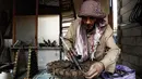 Seorang pengarajin yang bernama Abu Ali al-Bitar mengelem bekas peluru untuk menciptakan karya seni di Damaskus, Suriah (20/4). (AFP/Sameer Al-Doumy)