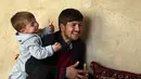 Asadullah Poya bersama anak laki-lakinya, Donald Trump saat wawancara di rumah kontrakan mereka di Kabul, Afghanistan, Kamis (15/3). Assadullah memutuskan menamai anaknya Donald Trump karena merupakan fans Presiden ke-45 AS tersebut. (AP/Rahmat Gul)