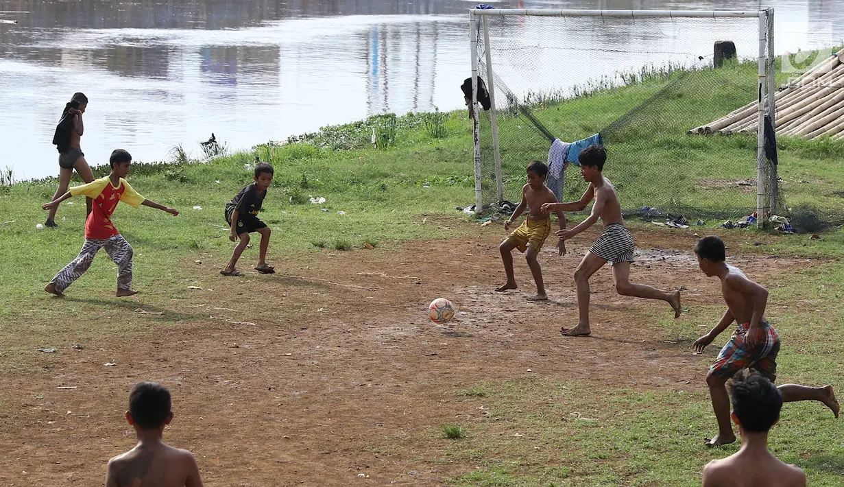 Anak-anak bermain sepak bola di bantaran Kanal Banjir Barat, Jakarta, Jumat (5/4). Tidak adanya lapangan menjadikan lokasi tersebut sebagai tempat bermain mereka, meskipun dalam kondisi seadanya. (Liputan6.com/Immanuel Antonius)