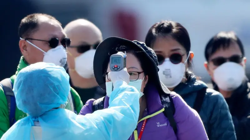 Petugas memeriksa suhu tubuh penumpang asing yang turun dari kapal pesiar Diamond Princess yang dikarantina di Yokohama, Jepang, Jumat (21/2/2020).