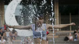 Seorang wanita menikmati bermain diantara air mancur saat menikmati musim panas di taman Gorky, Moskow, Rusia, Minggu (9/8/2015). (REUTERS/Sergei Karpukhin)