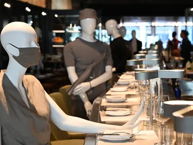 Maneken diletakkan di bar untuk menjaga jarak di sebuah restoran di Old Montreal, Kanada pada 10 Juli 2020. Restoran ini menempatkan maneken untuk menjaga jarak konsumen dan didandani dengan baju-baju keluaran terkini yang dapat dibeli pengunjung setelah makan. (Eric THOMAS/AFP)