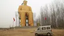 Sebuah mobil terlihat parkir di depan patung Presiden pertama Cina, Mao Zedong saat proses penyelesaian pembangunannya di ladang Desa Tongxu, Henan, Cina (4/1). Patung ini memiliki tinggi 36,6 meter dan dilapisi cat emas. (Reuters/Stringer)