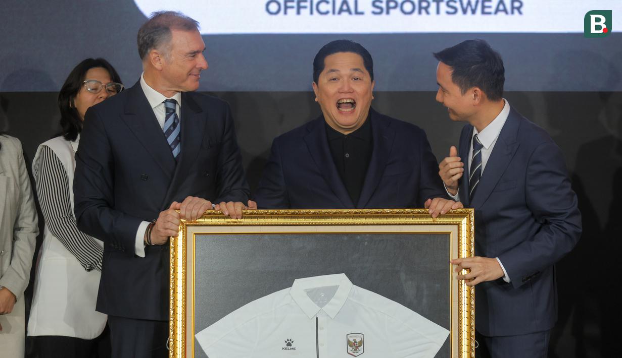 Ketua Umum PSSI, Erick Thohir (tengah) tertawa saat mendapatkan cendera mata kaos polo dari Chairman of CEO Kelme Global Clinten KE (kanan) dan Vice Chairman of Kelme Global, Borja Garcia Nieto (kiri) dalam acara perkenalan kerja sama yang berlangsung di Hotel Tribrata, Jakarta, Jumat (23/01/2026). (Bola.com/Bagaskara Lazuardi)