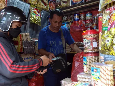 Pedagang kue kering melayani pembeli di salah satu toko di kawasan Ciracas, Jakarta, Kamis (19/4/2023). (Liputan6.com/Herman Zakharia)
