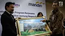 Chief Operating Officer IJN Kuala Lumpur Akmal Arief Mohamed Fauzi memberi lukisan kepada Direktur Retail Banking Bank Mandiri Tardi saat penandatanganan perjanjian kerjasama di Jakarta, Rabu (6/9). (Liputan6.com/Angga Yuniar)