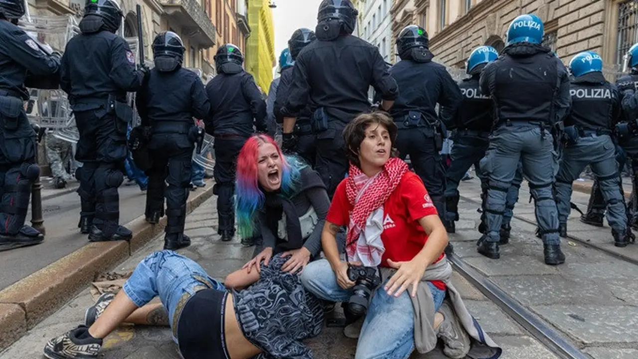 Sejumlah demonstran berlindung di belakang barisan polisi setelah terjadi bentrokan dalam aksi protes terhadap tingginya biaya hidup di Milan, Italia, Sabtu (17/10/2026).