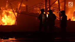 Petugas damkar berusaha menjinakan api yang membakar kapal nelayan di Pelabuhan Muara Baru, Penjaringan, Jakarta Utara, Sabtu (23/2). Sebanyak 18 kapal nelayan terbakar yang belum diketahui penyebabnya. (merdeka.com/Imam Bukhori)