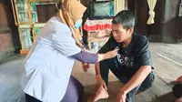 Dokter dari Puskesmas Air Itam saat mengecek kondisi LK, pasien ODGJ di ketika melakukan kunjungan ke rumah pasien di Kecamatan Penukal Kabupaten PALI Sumsel (Liputan6.com / Nefri Inge)