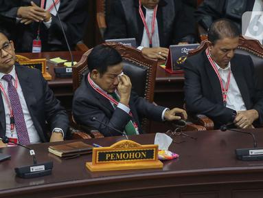 Calon wakil presiden nomor urut 1 Muhaimin Iskandar mengusap wajahnya dengan tisu di sebelah calon presiden Anies Baswedan saat mengikuti jalannya sidang putusan perselisihan hasil Pilpres 2024 di Gedung Mahkamah Konstitusi (MK), Jakarta, Senin (22/4/2024). (Liputan6.com/Angga Yuniar)