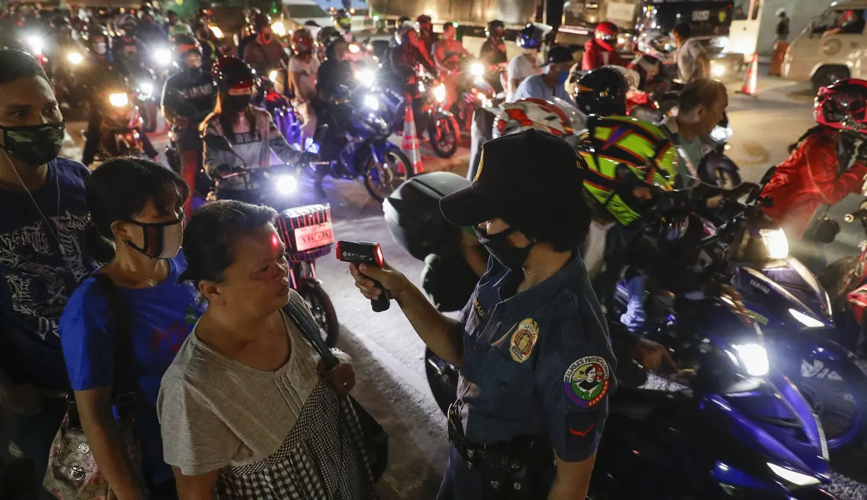 Polisi memeriksa suhu tubuh warga di pos pemeriksaan virus corona COVID-19 di Manila, Filipina, Senin (16/3/2020). Polisi beserta petugas lalu lintas dan petugas desa melakukan pengecekan suhu tubuh warga untuk mencegah penyebaran virus corona COVID-19. (AP Photo/Aaron Favila)