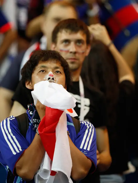 Suporter Jepang memeluk bendera negaranya usai pertandingan melawan Belgia pada babak 16 besar Piala Dunia 2018 di Rostov Arena, di Rostov-on-Don, Rusia, (2/7). Jepang takluk dengan dramatis atas Rusia 3-2. (AFP Photo / Odd Andersen)
