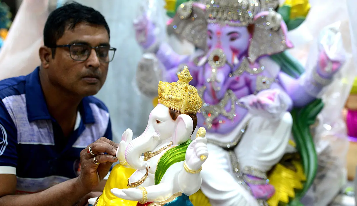 Seorang perajin mengerjakan pembuatan patung Dewa Ganesha di sebuah bengkel di Mumbai, India, 24 Agustus 2021. Pembuatan patung dewa Hindu berkepala gajah tersebut dilakukan jelang Festival Ganesh Chaturthi. (SUJIT JAISWAL/AFP)