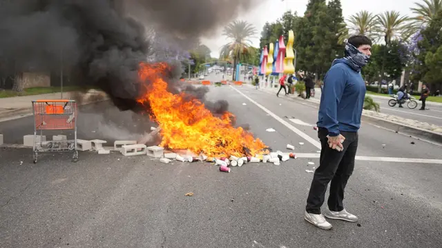Kebakaran selama demonstrasi terhadap puluhan orang yang ditahan dalam operasi oleh agen ICE di kawasan Paramount, Los Angeles (LA), Jumat (6/6/2025). (AP)