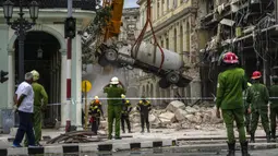 Petugas pemadam kebakaran menyemprot truk tangki dengan air untuk mendinginkannya saat mereka memindahkannya dari lokasi ledakan mematikan yang menghancurkan Hotel Saratoga di Havana, Kuba, 6 Mei 2022. Ledakan kuat yang diduga disebabkan oleh kebocoran gas alam menewaskan 18 orang dan melukai puluhan orang. (AP Photo/Ramon Espinosa)