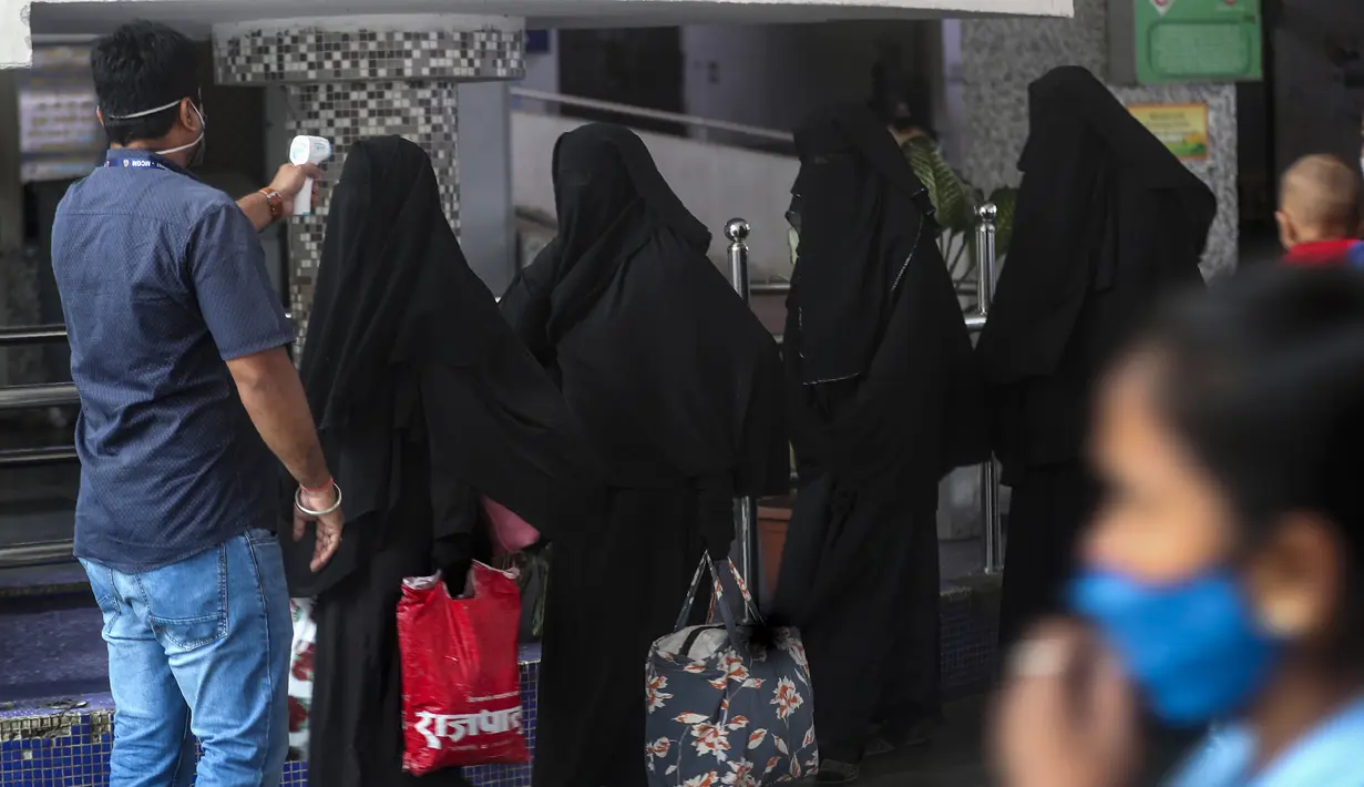 Petugas kesehatan memeriksa suhu penumpang saat melakukan skrining untuk tes COVID-19 di stasiun kereta jarak jauh di Mumbai, Maharashtra, Minggu (21/3/2021). India mencatat rekor lonjakan harian tertinggi dalam hampir empat bulan terakhir. (Ap Photo/Rafiq Maqbool)