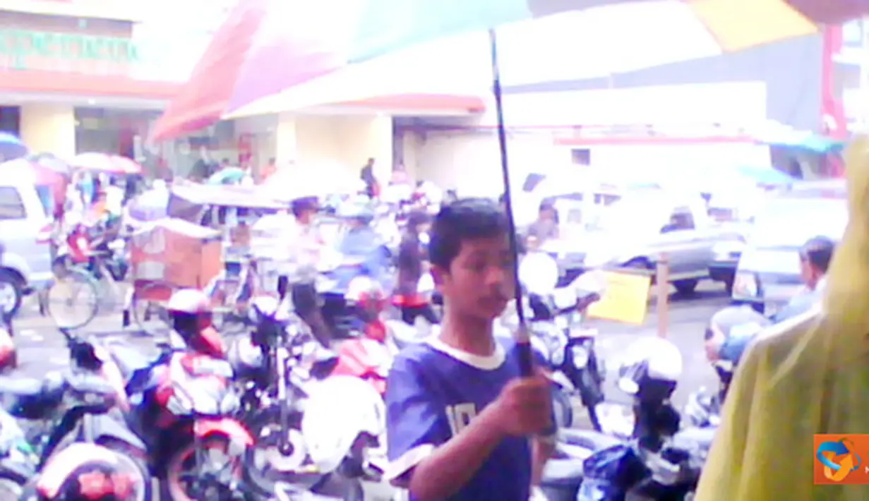 Citizen6, Tasikmalaya: Seorang anak sedang berusaha menawarkan payung untuk digunakan pejalan kaki.