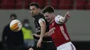 Bek Arsenal, Kieran Tierney (kanan) berebut bola dengan gelandang Benfica, Pizzi dalam laga leg kedua babak 32 Besar Liga Europa 2020/21 di Georgios Karaiskakis Stadium, Kamis (25/2/2021). Arsenal menang 3-2 atas Benfica. (AP/Thanassis Stavrakis)