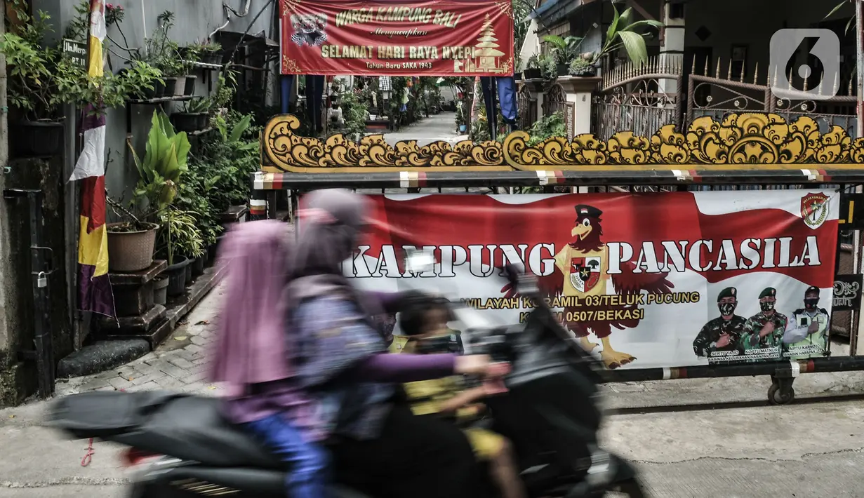 Pengendara sepeda motor melintas di depan salah satu pintu masuk Kampung Bali saat perayaan Hari Nyepi, Harapan Jaya, Bekasi, Jawa Barat, Minggu (14/3/2021). Toleransi beragama untuk saling menghormati di kampung ini sangat terjaga. (merdeka.com/Iqbal S. Nugroho)