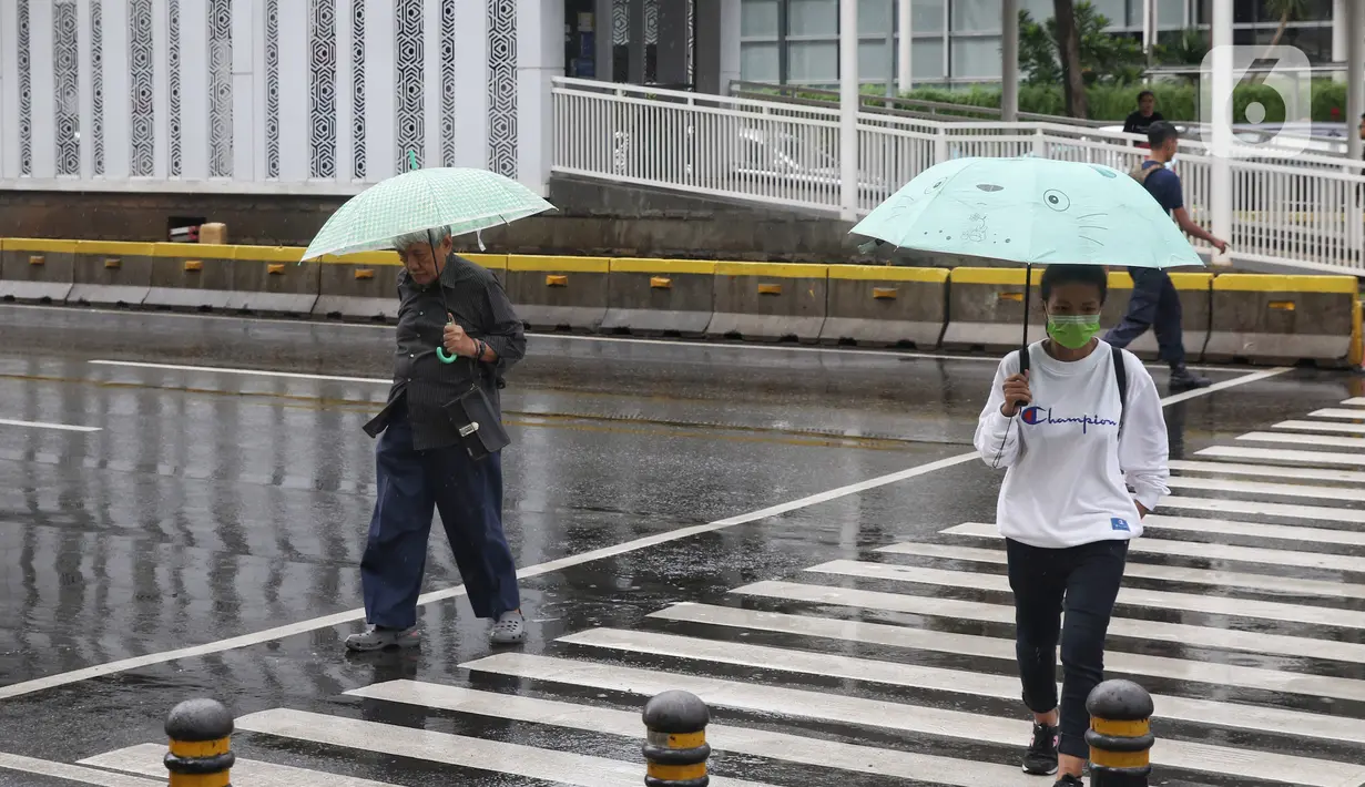 Pejalan kaki melintas menggunakan payung saat hujan mengguyur kawasan Jakarta, Senin (3/2/2020). Diperkirakan sejumlah wilayah berpotensi diguyur hujan dengan intensitas lebat hingga disertai dengan angin kencang, kilat/petir hingga Rabu (5/2/2020) mendatang. (Liputan6.com/Angga Yuniar)