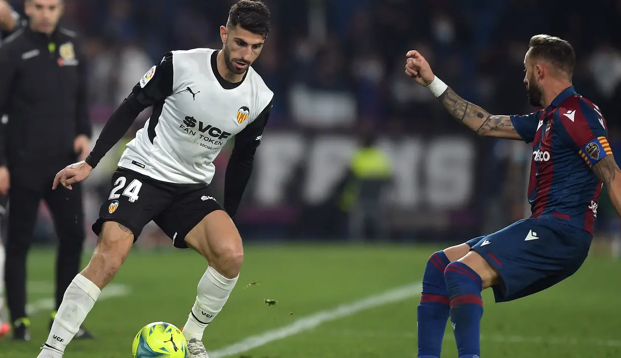 Gelandang Levante, Jose Luis Morales berusaha melewati bek Valencia, Cristiano Piccini pada pertandingan lanjutan La Liga Spanyol di stadion Ciutat de Valencia di Valencia (20/12/2021).  Hasil ini membuat Valencia naik satu peringkat ke posisi ketujuh klasemen dengan 28 poin. (AFP/Jose Jordan)