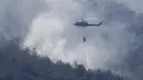Helikopter tentara Lebanon menjatuhkan air di atas kebakaran hutan, di desa Qobayat, Lebanon, Kamis (29/7/2021). Petugas pemadam kebakaran Lebanon berjuang di hari kedua untuk mengatasi kebakaran hutan di utara negara itu yang telah menyebar ke seluruh perbatasan ke Suriah. (AP Photo/Hussein Malla)