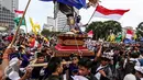 Seorang peserta menaiki Ogoh-ogoh membawa bendera merah putih saat aksi Kita Indonesia di kawasan Bundaran HI, Jakarta, Minggu (04/12). Aksi tersebut adalah acara perayaan kegembiraan atas keberagaman dan kebangsaan Indonesia. (Liputan6.com/Fery Pradolo)