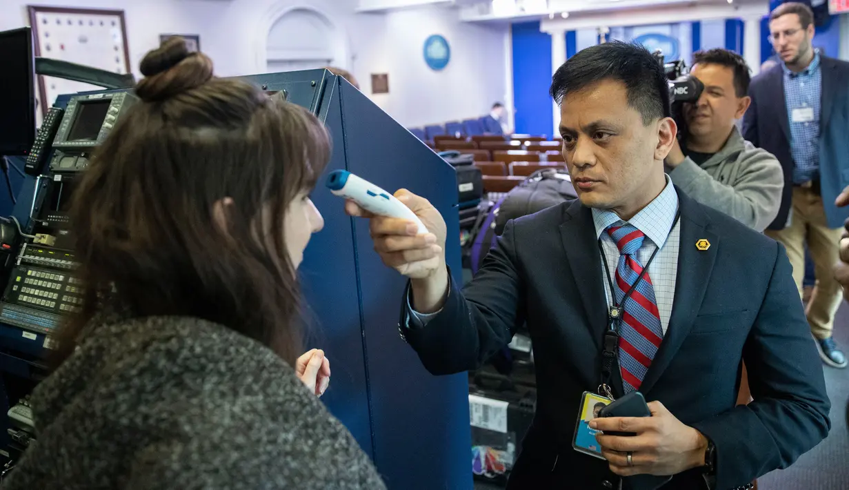 Anggota kantor dokter Gedung Putih memeriksa suhu jurnalis di luar Brady Press Briefing Room sebelum konferensi pers di Washington, Minggu (15/3/2020). Gedung Putih memberlakukan sejumlah langkah-langkah baru untuk melindungi Donald Trump dan stafnya dari virus Corona COVID-19. (AP/Alex Brandon)