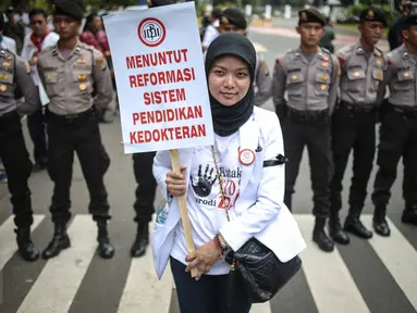 Seorang dokter membawa poster saat melakukan aksi unjuk rasa di Ibu Kota hari ini, Senin (24/10). Demo itu untuk menuntut pemerintah agar membatalkan Program Dokter Layanan Primer (DLP). (Liputan6.com/Faizal Fanani)