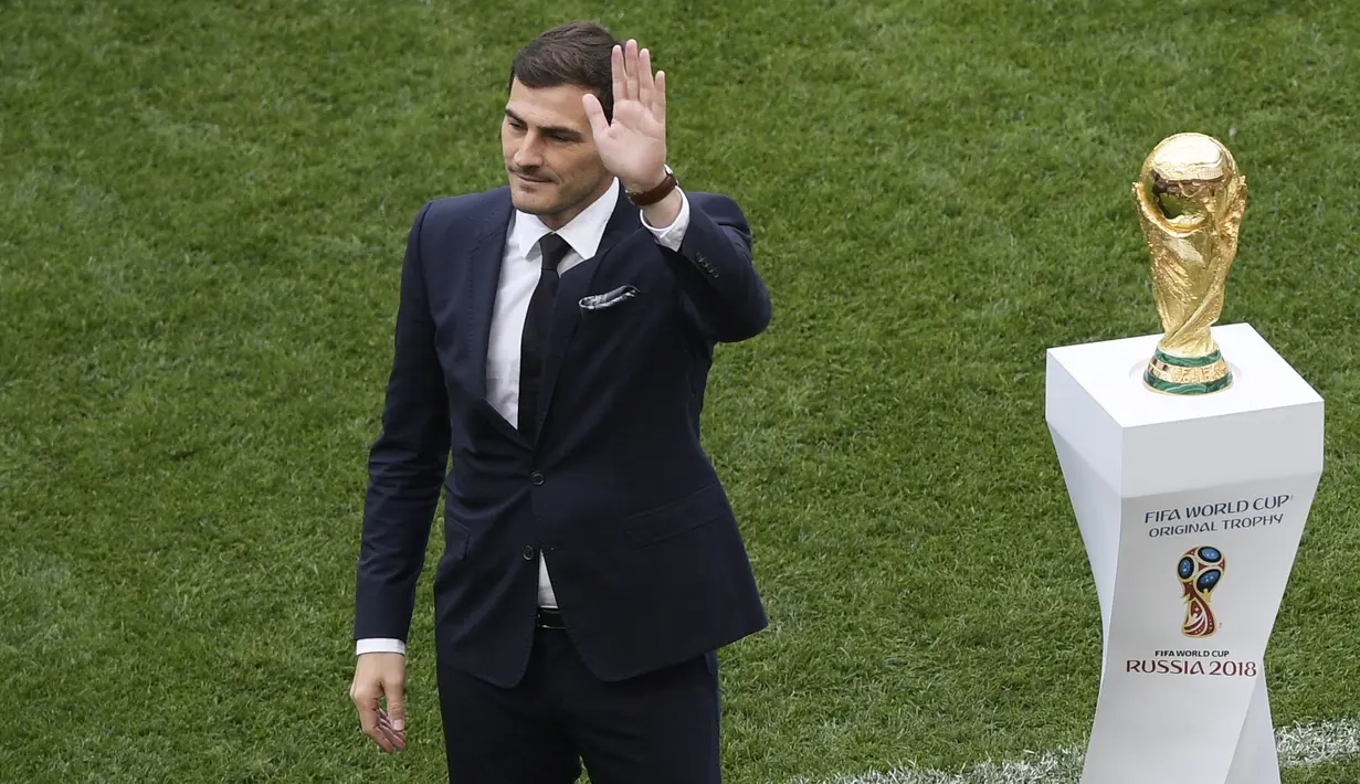 Mantan kiper timnas Spanyol, Iker Casillas melambaikan tangan di samping trofi Piala Dunia 2018 sebelum laga pembuka di stadion Luzhniki, Kamis (14/6). Trofi itu memiliki tinggi 36 centimeter dan berat 6,175 kg dengan 18 karat emas. (AFP/Mladen ANTONOV)