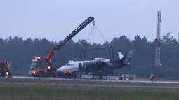 Alat berat mengangkat pesawat Cessna 560XL yang terbakar saat mendarat di Bandara Aarhus di Tirstrup (6/8/2019). Pesawat terbakar akibat roda mogok saat ingin mendarat dan pesawat mulai miring dan kebakaran terjadi di sisi kiri pesawat. (Oexenholt Foto/Ritzau Scanpix/AFP)