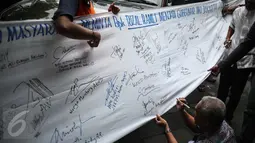 Seorang pria membubuhkan tanda tangan di spanduk putih guna dukungan untuk Rizal Ramli sebagai bakal calon gubernur DKI 2017, Jakarta, Senin (8/8). Aksi tersebut dilakukan oleh Konferederasi Serikat Pekerja Indonesia (KSPI). (Liputan6.com/Faizal Fanani)