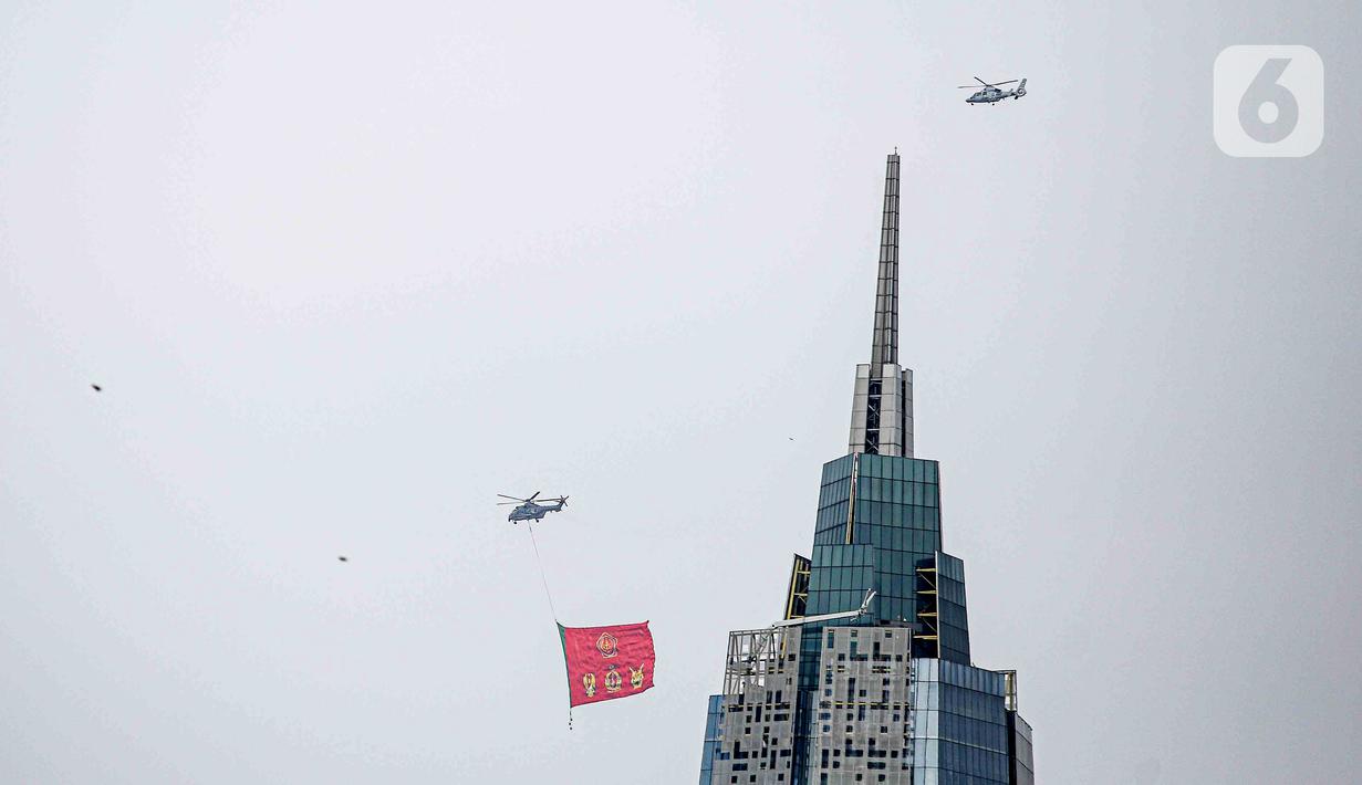 Helikopter TNI AU mengibarkan bendera Trimatra raksasa di kawasan Gedung DPR RI, Jakarta, Selasa (5/10/2021). Bendera yang dikibarkan berukuran 30 x 20 meter. (Liputan6.com/Faizal Fanani)