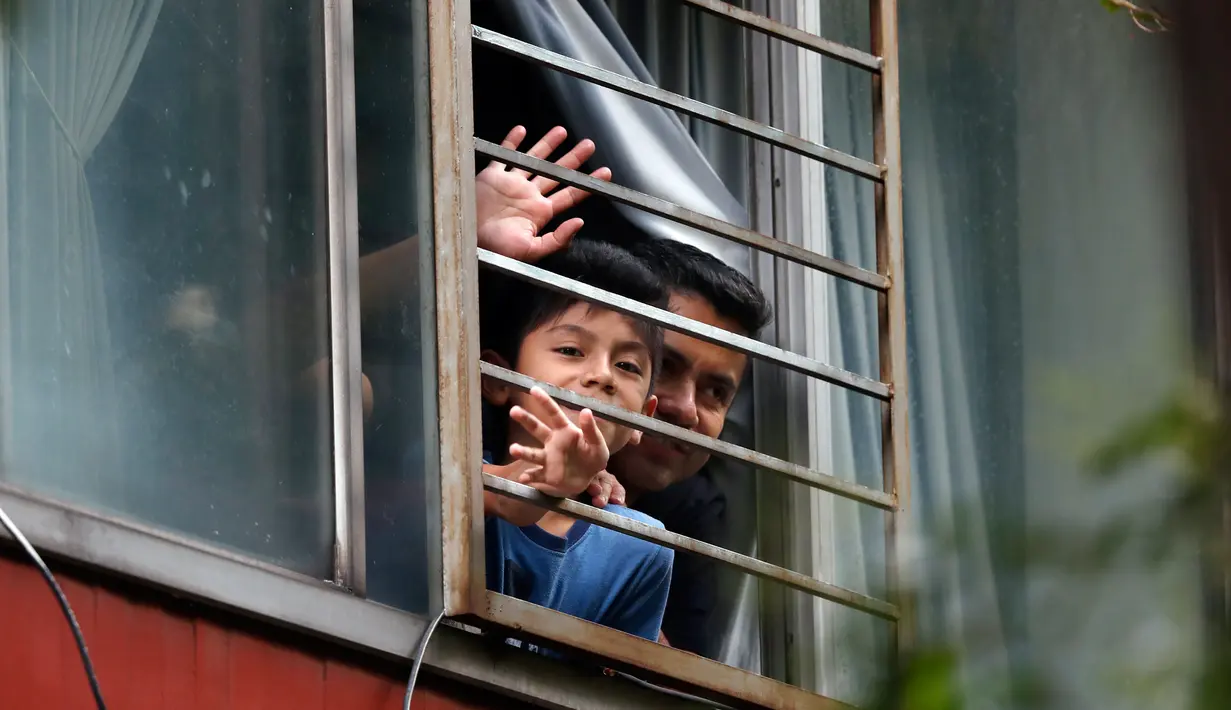 Penduduk melambaikan tangan ketika Percibald Garcia membaca buku untuk anak-anak dengan pengeras suara di kompleks perumahan Tlatelolco di Mexico City pada 18 Juli 2020. Lockdown akibat pandemi corona membuat arsitek muda itu memutuskan untuk berbagi cerita menghibur anak-anak. (AP/Marco Ugarte)